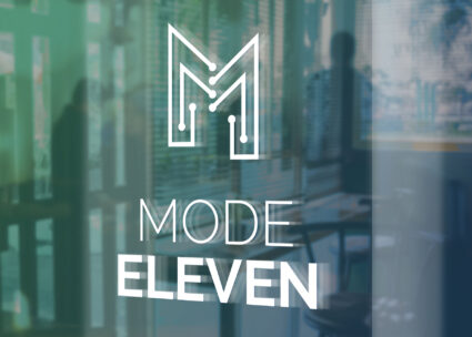 A Mode Eleven logo displayed on a glass office door